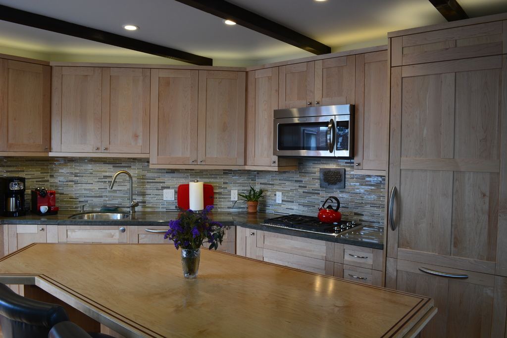 A bright kitchen with pale timber cabinets, a mosaic backsplash and a large island