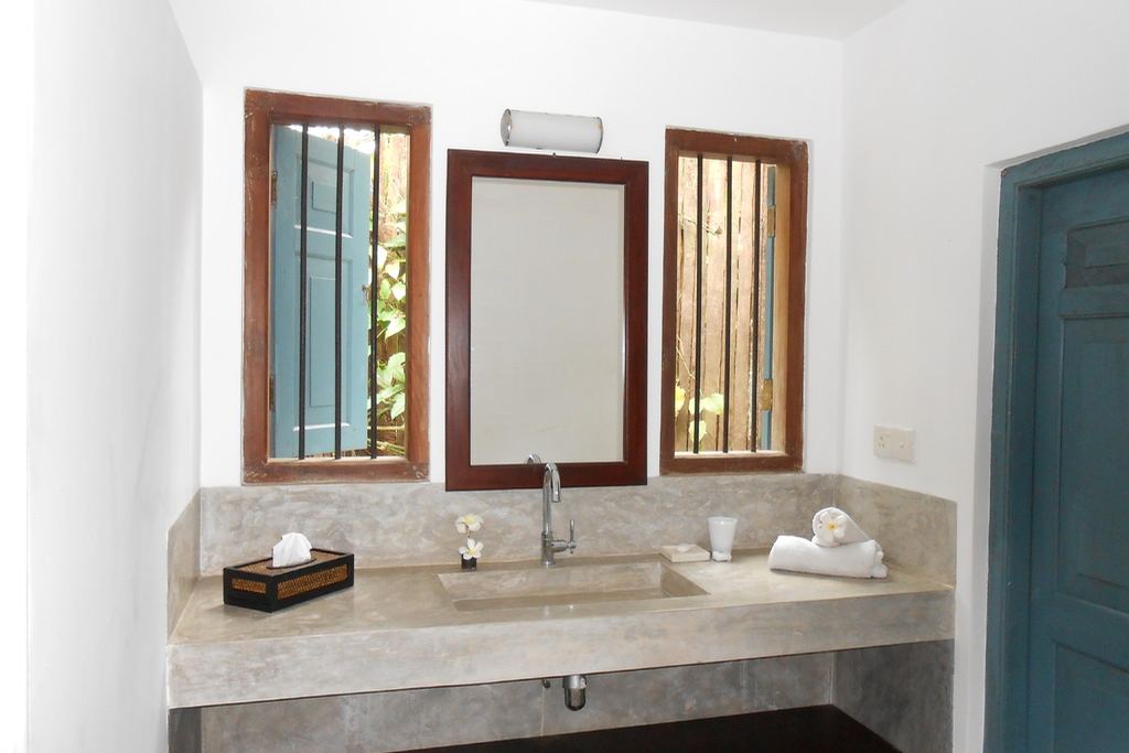 A bright bathroom with a stone vanity, timber-framed mirrors and a blue door